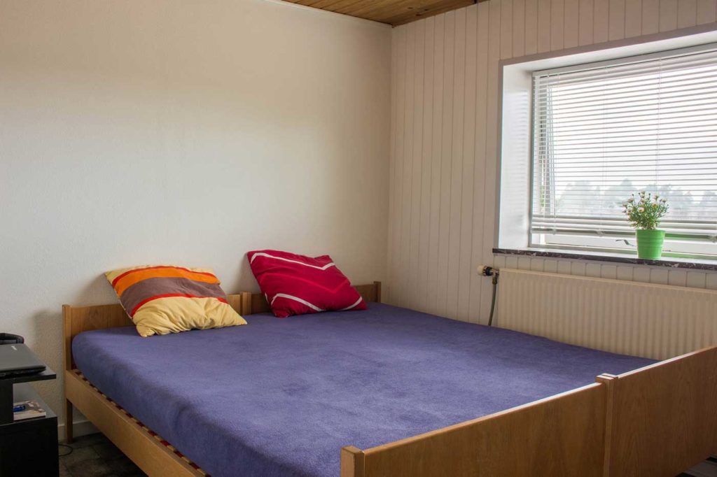 Det ene soveværelse med dobbelt seng ved indgangen til lejligheden